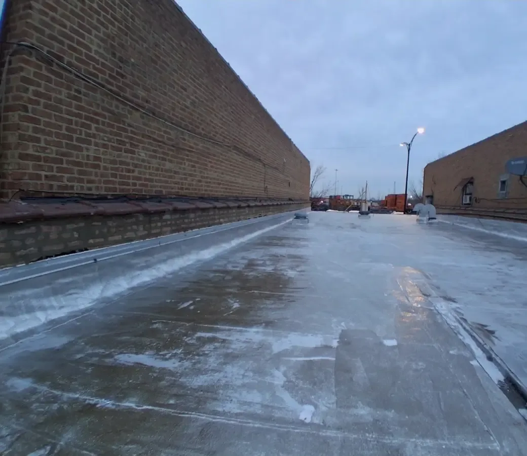 Completed flat roof running the length of the building between two brick parapets