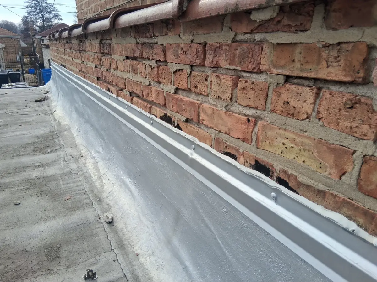 New metal edge flashing installed where the parapet meets the roof membrane
